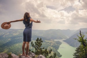 energy renewal a woman standing on mountain top with open arms